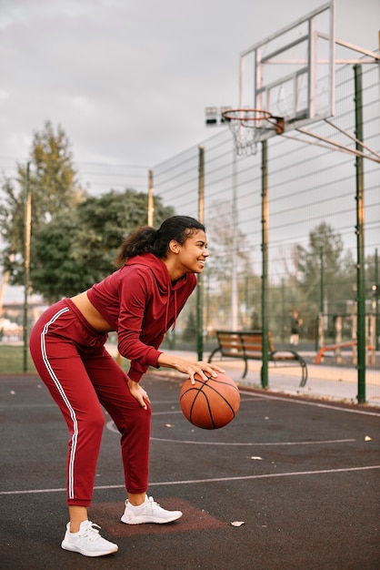 Black american woman playing basketball on a field