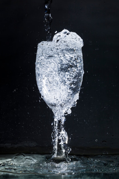 Black background with overflowing glass of water