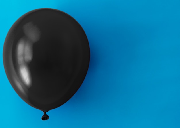 Free Photo black balloon on blue background with copy space