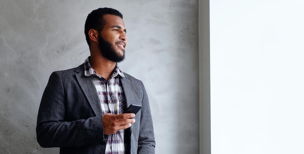 Black bearded male dressed in a fleece shirt and a jacket using a smart phone.