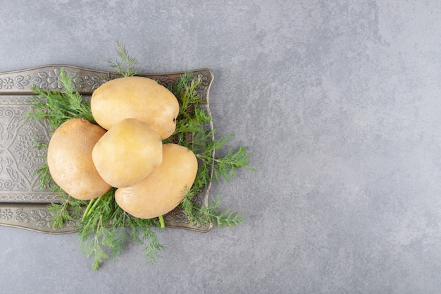 A black board of uncooked potatoes with fresh dill 