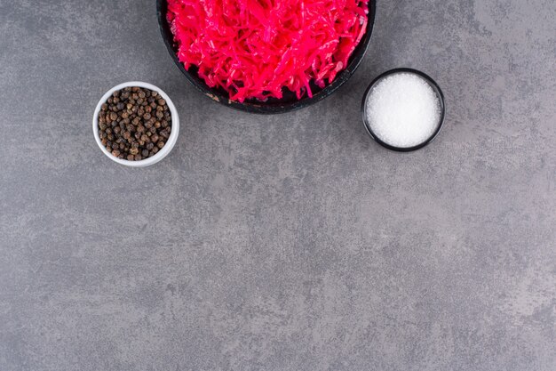 Black bowl of pickled red cabbage on stone table.