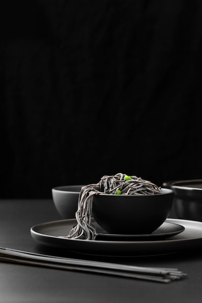 Black bowl with pasta on a dark plate