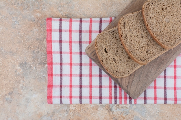 Black bread slices on wooden board with tablecloth