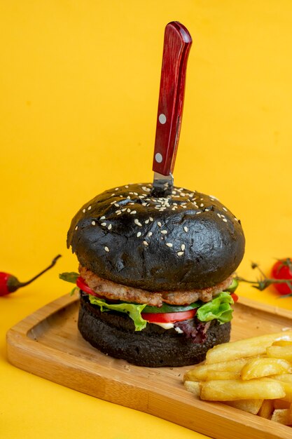 Black burger with knife inside and fries