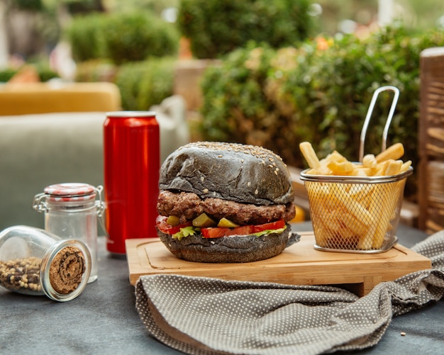 Black burger with side fries and cola