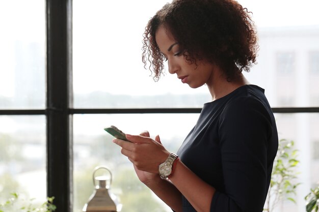 Black business woman in strict black dress checking her emails at the phone