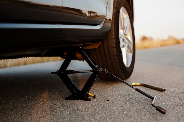 Free Photo black car lifted up by a jack-screw