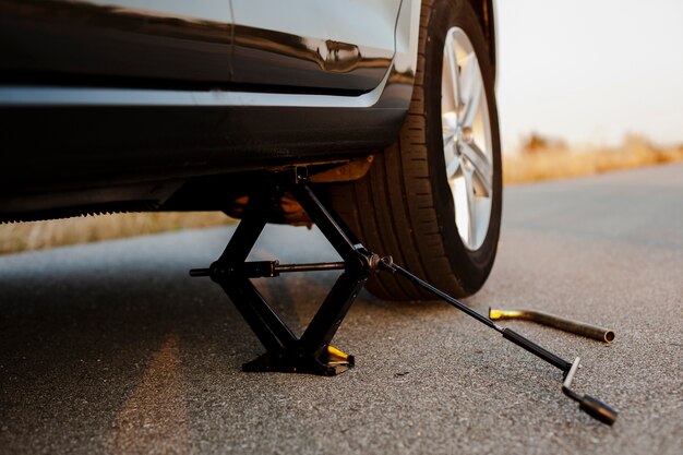 Black car lifted up by a jack-screw