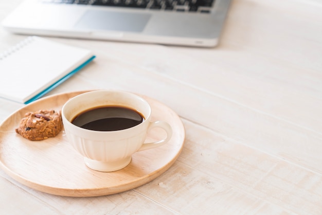 black coffee and cookies with laptop and note book