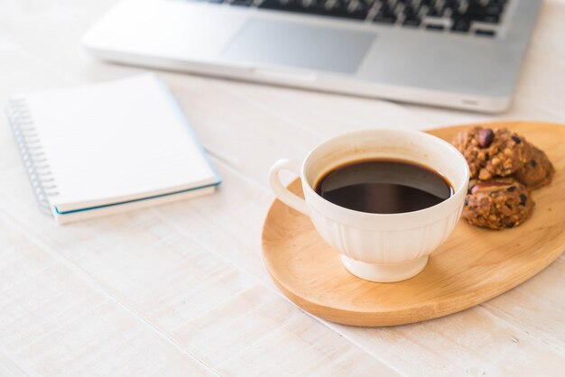 black coffee and cookies with laptop and note book