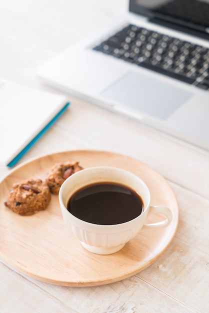 black coffee and cookies with laptop and note book