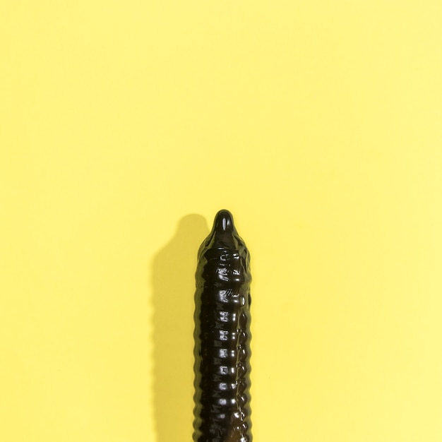 Free photo black condom on yellow background with copy-space