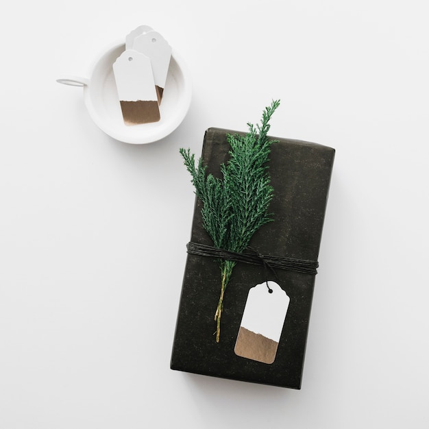 Free photo black gift box with cypress branch on light table