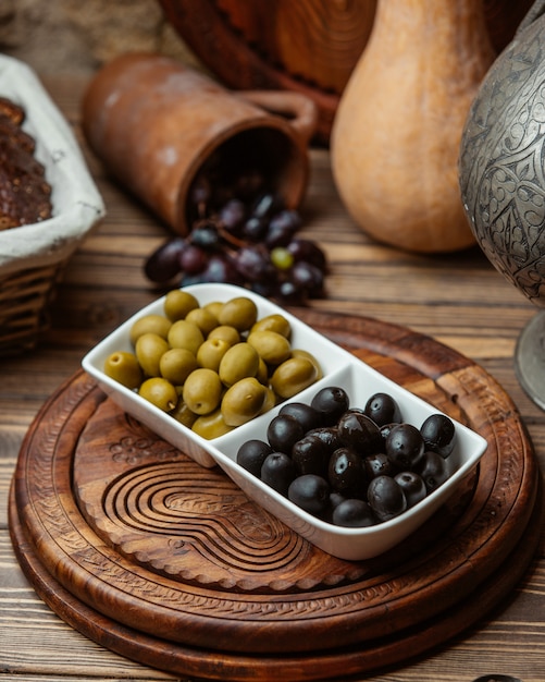 Black and green marinated olives in white bowl.