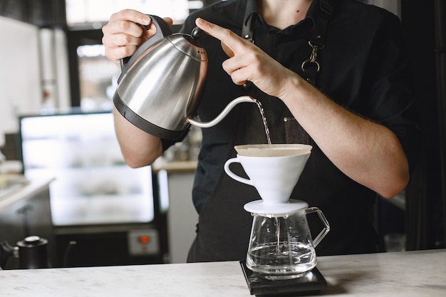 Free photo black ground coffee. barista brews a drink. coffee in a glass jug.