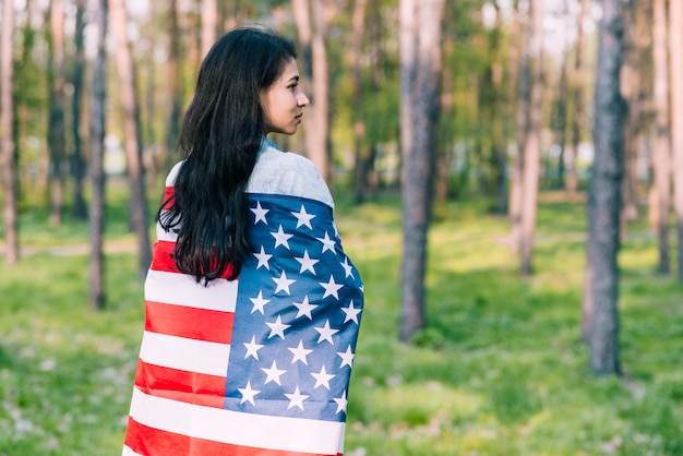 Black-haired female wrapped in flag of USA