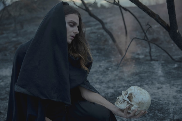 Free photo black hooded man with skull and autumn branches in background