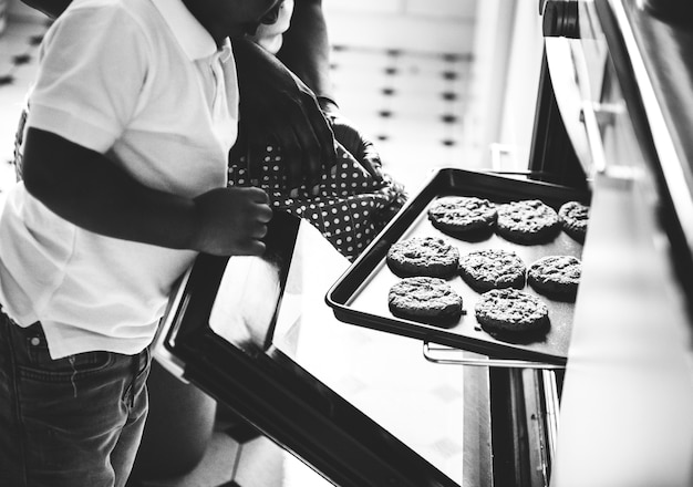 Free photo black kid helping mom baking cookies in the kitchen