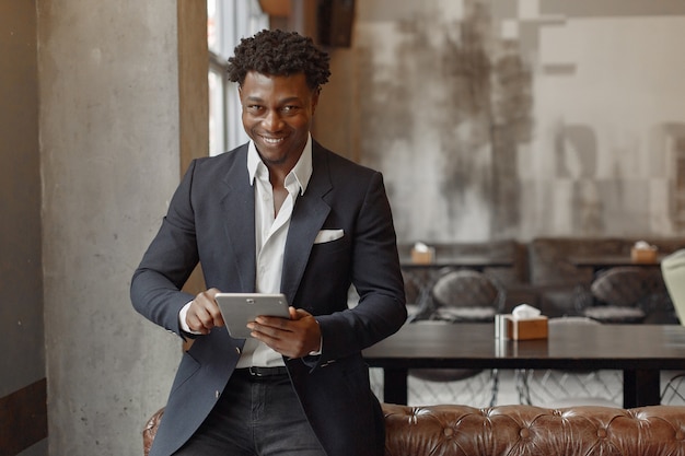 Black man in a black suit standing in a cafe