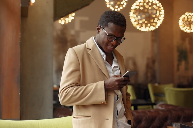 Black man in a brown coat standing with mobile phone