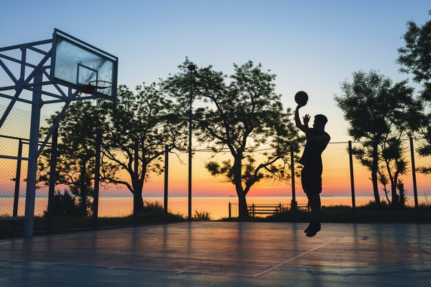 Black man doing sports, playing basketball on sunrise, jumping silhouette