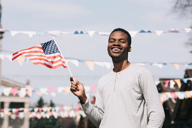 Free photo black man holding american flag and laughing