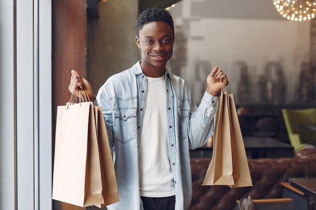 Black man standing in a cafe with shopping bags