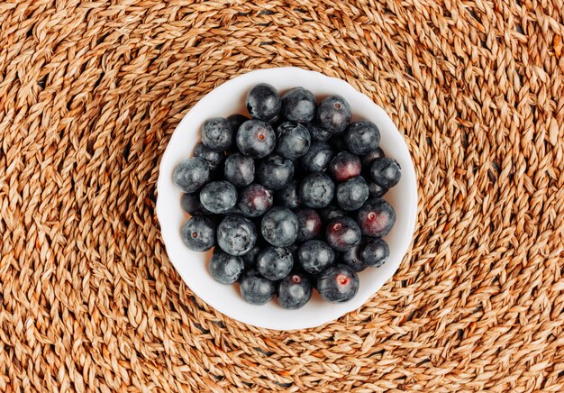 Black olives in a bowl on a rattan trivet background. top view.