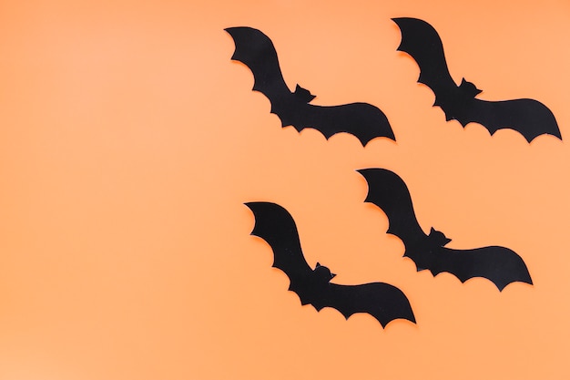 Free Photo black paper bats on orange background 