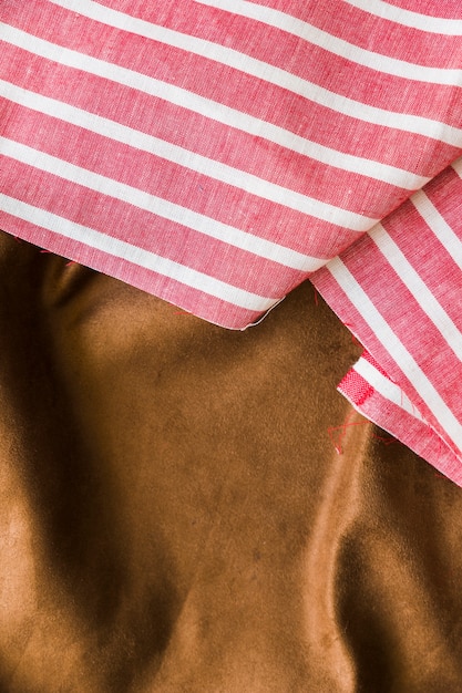 Black and red striped pattern fabric over the smooth brown textile