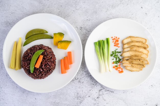 Black rice on a plate with pumpkin, peas, carrots, baby corn and steamed chicken breast.