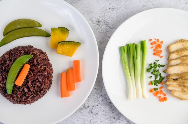 Black rice on a plate with pumpkin, peas, carrots, baby corn and steamed chicken breast.