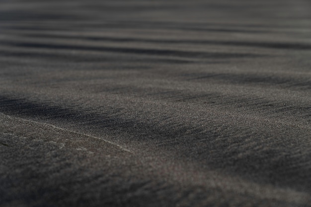 Free Photo black sand beach macro photography. silky black beach texture with shallow depth of field. minimalistic black background. tenerife voulcanic sandy shore.