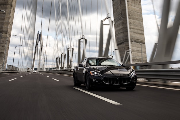 Black sedan car driving on the bridge road.