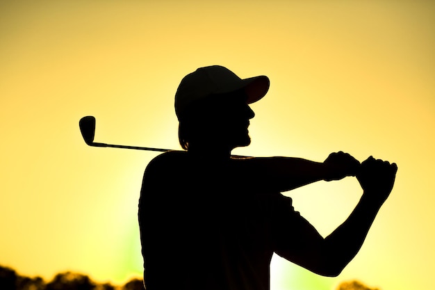 Free photo black silhouette closeup of male golf player with hat teeingoff at beautiful golf course professional golf player smiling