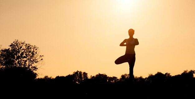 Black silhouette of yogi girl with her hands clasped on front of her chest. Beautiful girl with ideal back posture practicing.