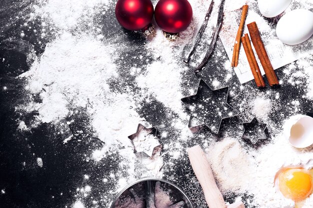 Black table full of flour and eggs with christmas decorations