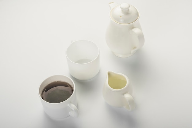 Black tea; milk jug; white cup and teapot isolated on white backdrop