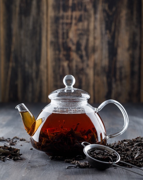 Black tea with dry tea in a teapot on wooden surface