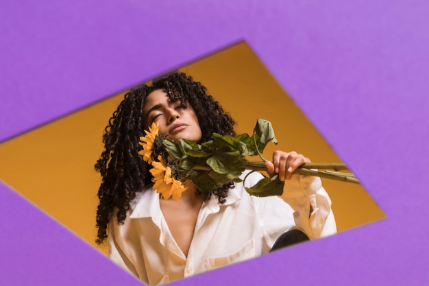 Free photo black thoughtful woman with flowers in hole in paper