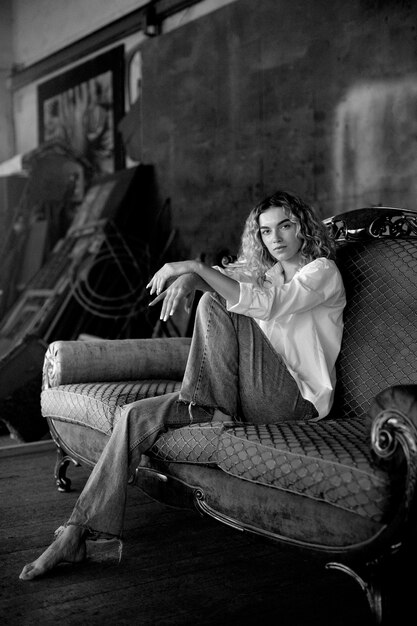 Black and white portrait of beautiful woman posing indoors on a couch