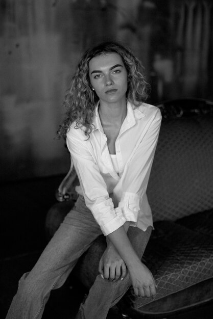 Black and white portrait of beautiful woman posing indoors on a couch