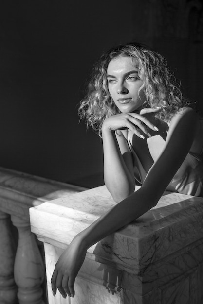 Black and white portrait of beautiful woman posing indoors in a dress