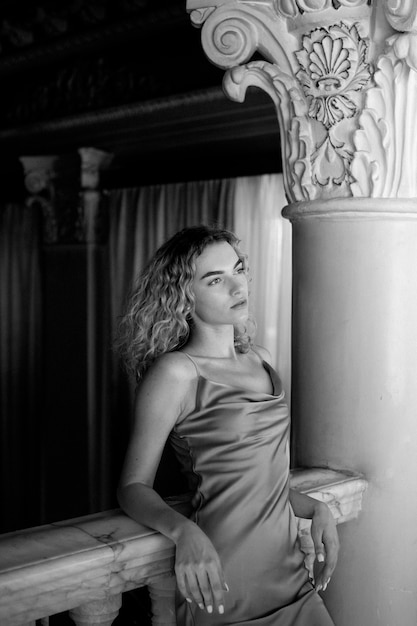 Free photo black and white portrait of beautiful woman posing indoors in a dress