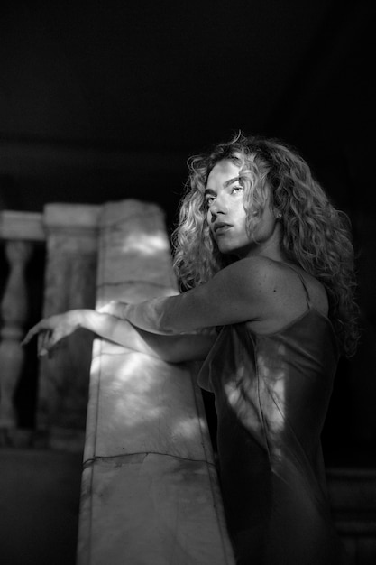 Black and white portrait of beautiful woman posing indoors in a dress