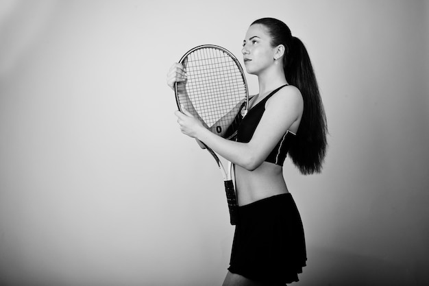 Free Photo black and white portrait of beautiful young woman player in sports clothes holding tennis racket while standing against white background