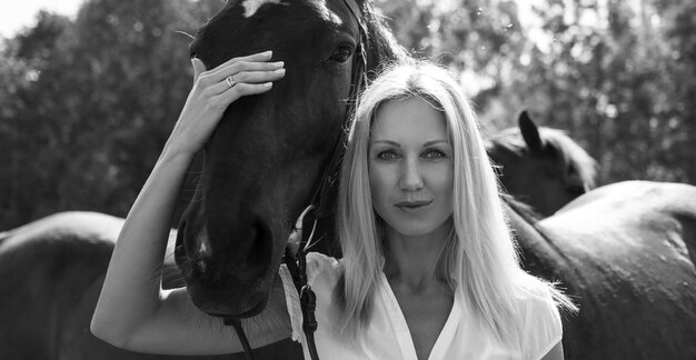 Black and white portrait of blond woman with horse.