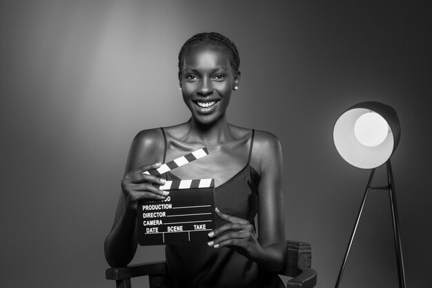 Black and white portrait of woman with clapperboard in old hollywood glamour style