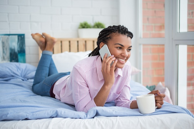 Black Woman Lying on Bed and Calling on Phone